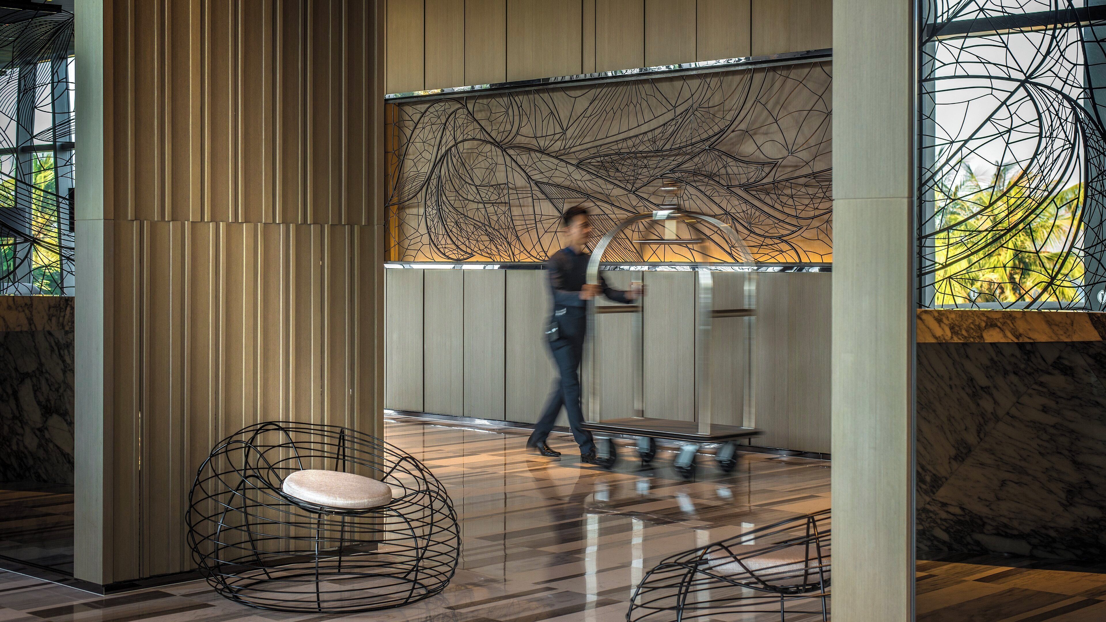 Een modern interieur met een persoon in beweging, een gebogen zithoek en een muur met abstracte patronen.