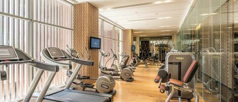 A modern gym with treadmills, elliptical machines, and weight equipment.