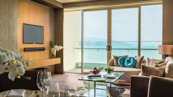 Une chambre d’hôtel avec un balcon, une télévision, une table à manger et un canapé agrémenté de coussins décoratifs.