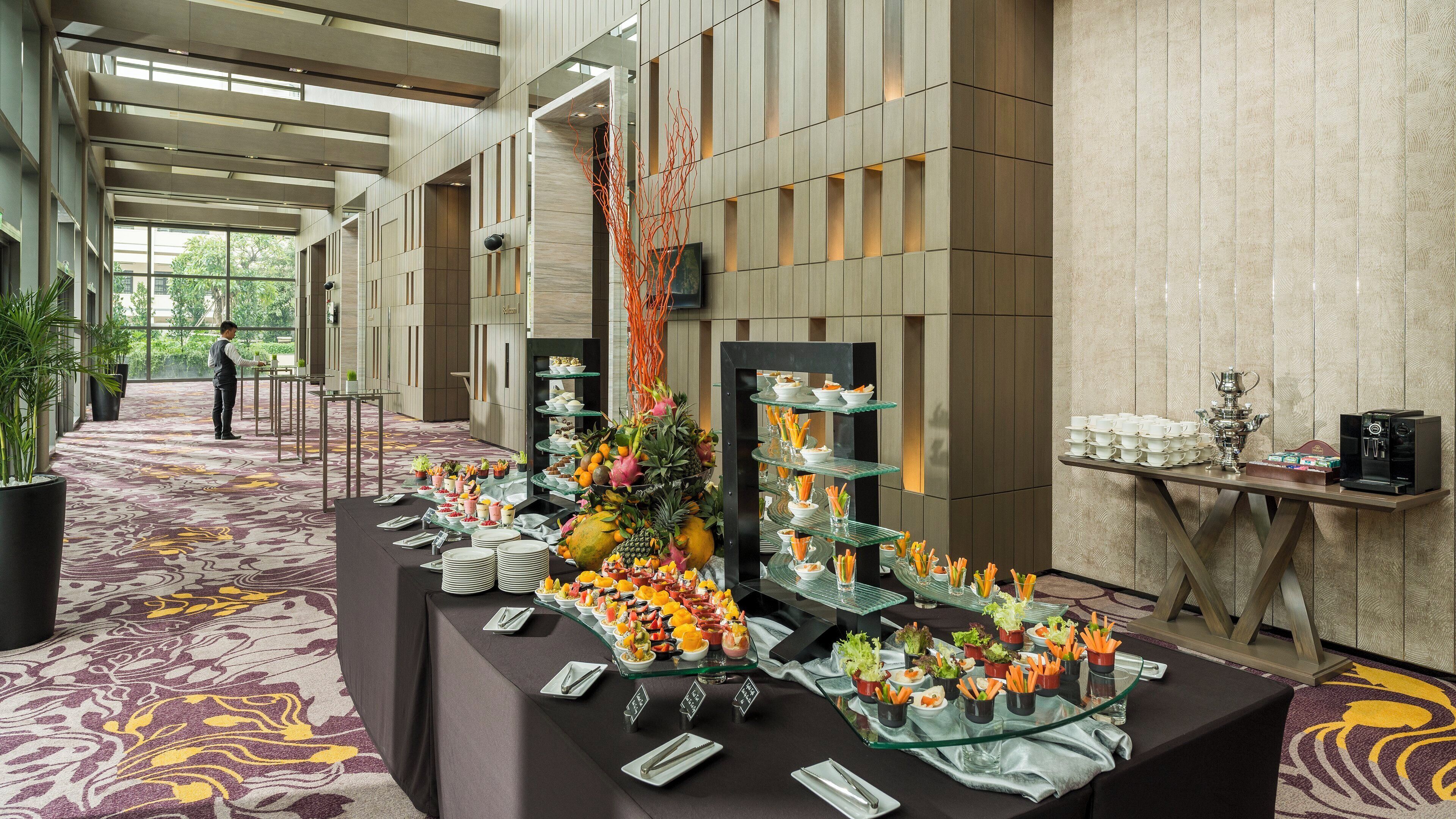 A buffet setup with various food items and a coffee machine in a modern hotel setting.