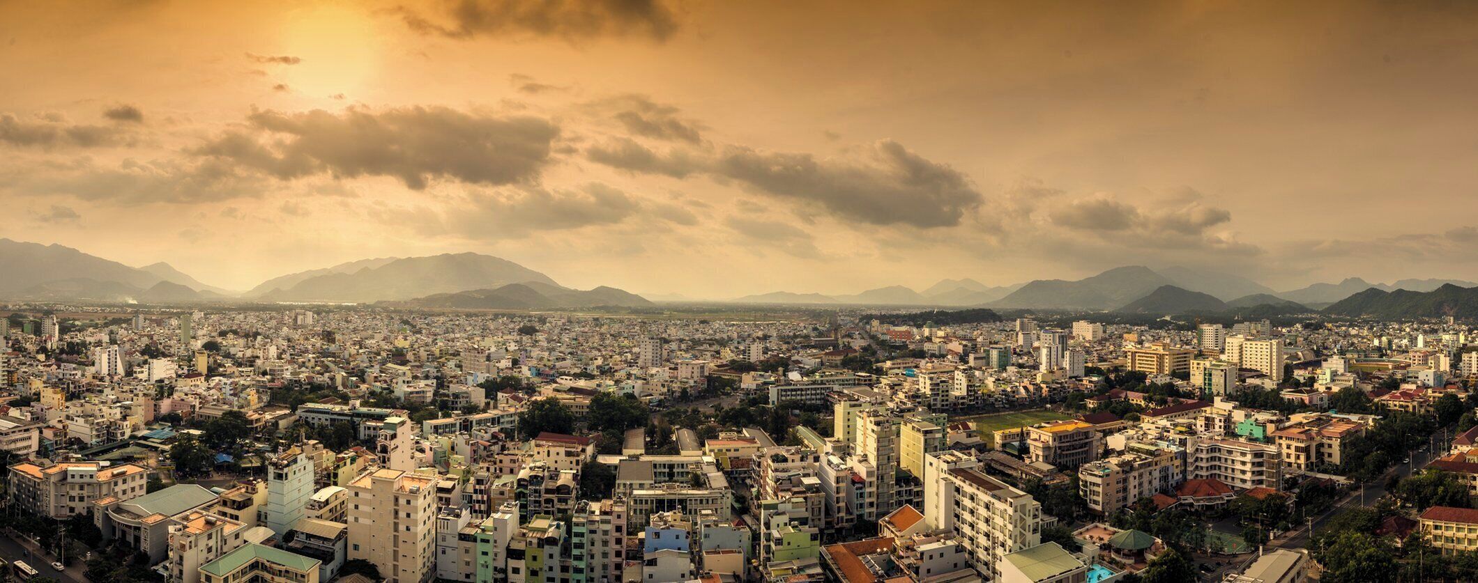 A cityscape with a dense urban area, buildings, and mountains in the background.