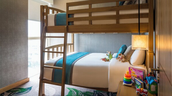 A bunk bed with a ladder, a bedside table with toys, and a lamp.