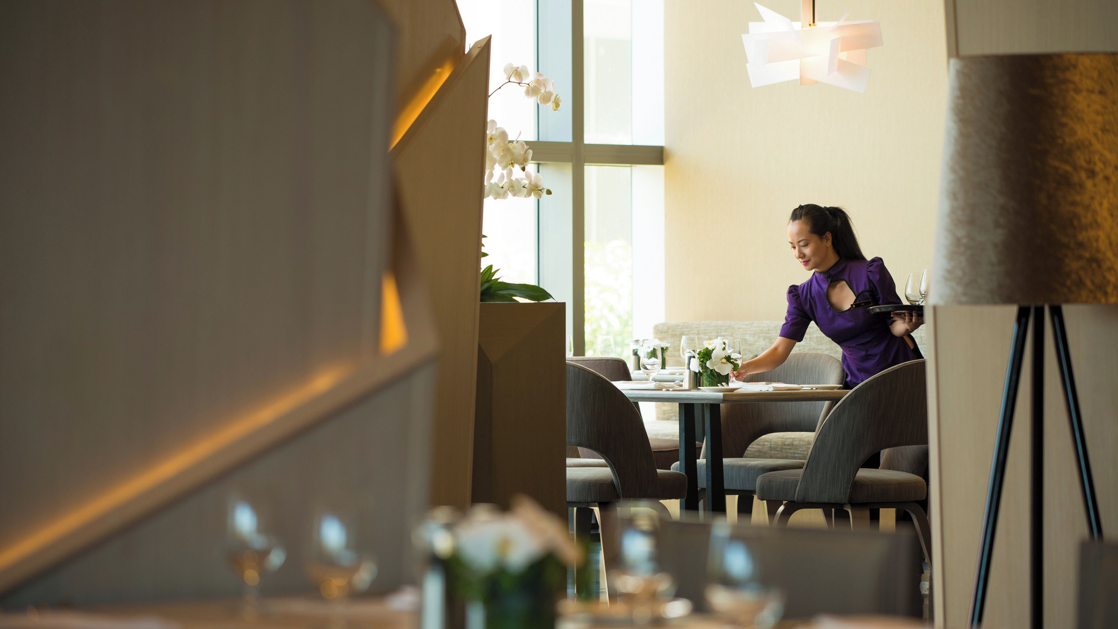 Ein Essbereich mit Tisch für zwei Personen, einer sitzenden Person und modernem Interieur.