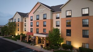 Ein mehrgeschossiges Hotel mit der Beschriftung "TownePlace Suites by Marriott". Es hat eine Ziegel-Fassade, zahlreiche Fenster und einen begrünten Eingangsbereich.