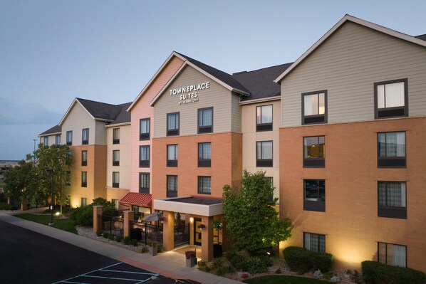 A multi-story hotel with a sign reading "TownePlace Suites by Marriott." It features a brick facade, multiple windows, and a landscaped entrance area.