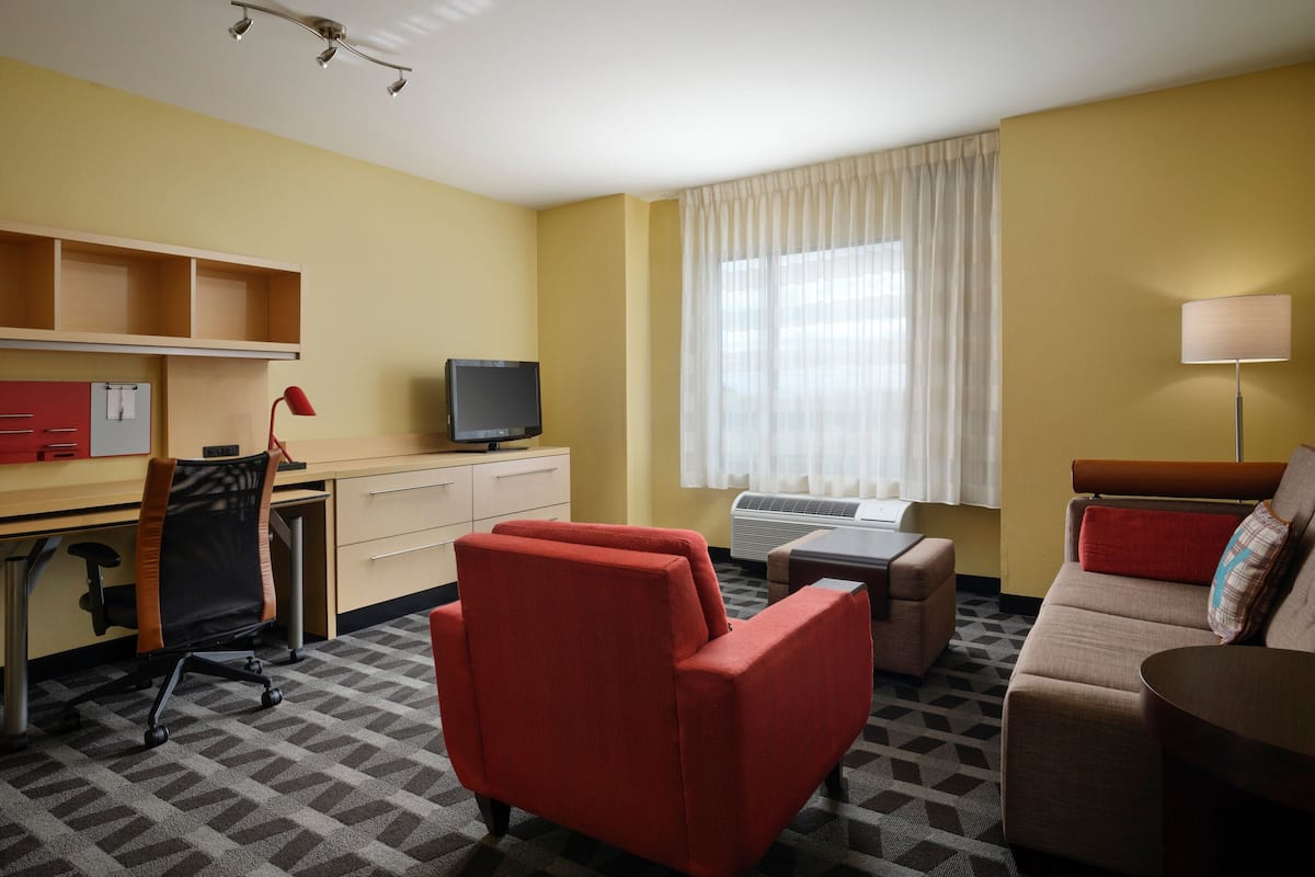 Une chambre d’hôtel équipée d’un bureau, d’un fauteuil de bureau, d’un canapé et d’une télévision.