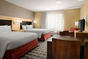 Une chambre d’hôtel avec deux lits, un bureau, une chaise, une télévision et une fenêtre avec des rideaux.