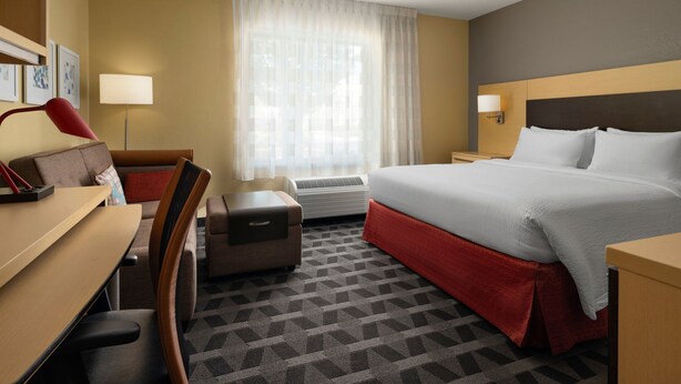 Ein Hotelzimmer mit Bett, Schreibtisch, Stuhl und einem Fenster mit Vorhängen.