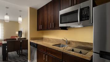 A modern kitchen with dark wooden cabinets, stainless steel appliances, and a granite countertop.