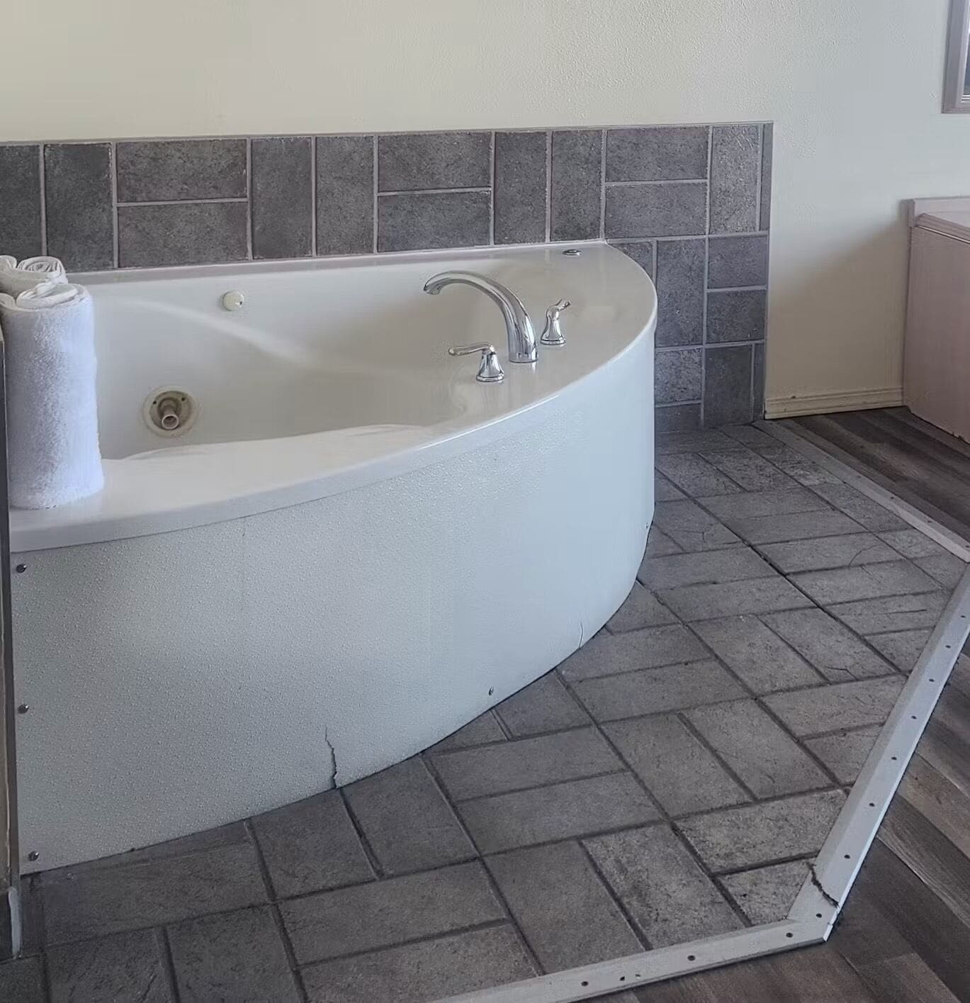 Une salle de bain moderne avec une baignoire sur pieds, des murs carrelés en gris et un sol carrelé également en gris.
