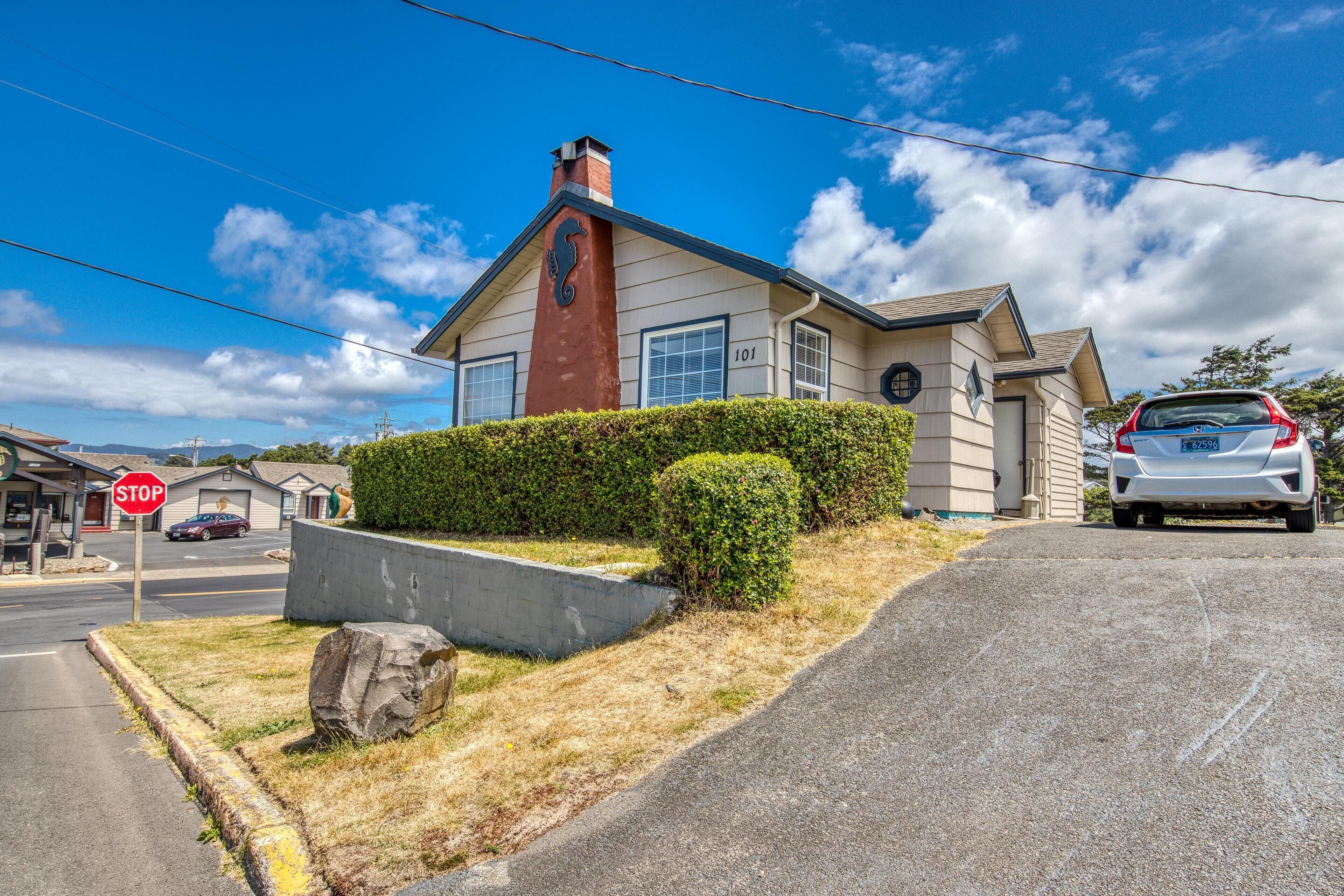 A two-story house with a chimney, a stop sign, and a parked car.