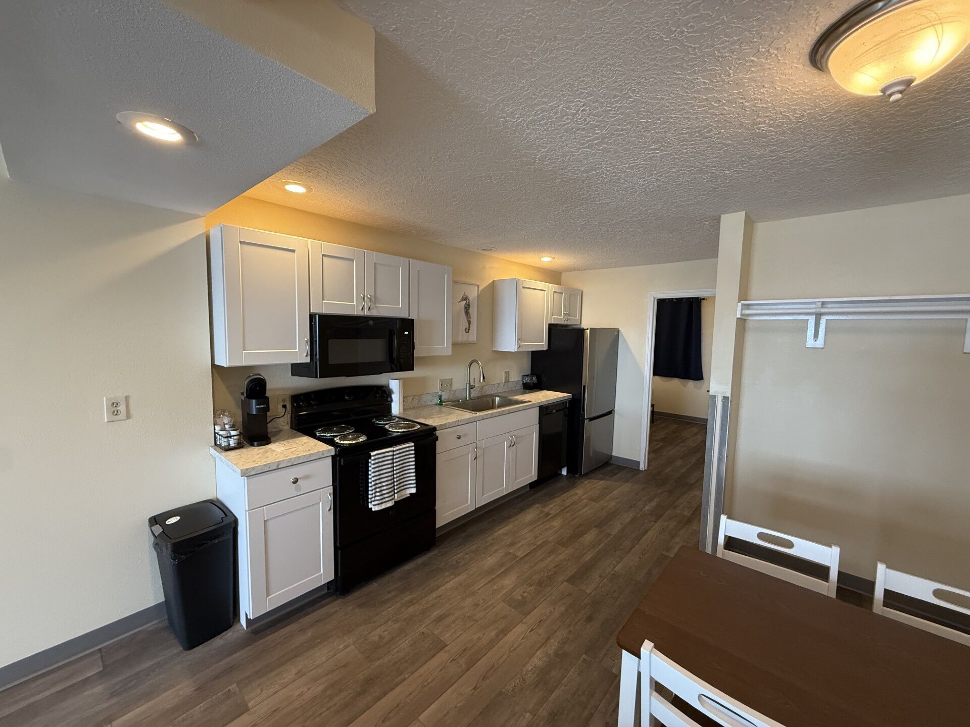 A compact kitchen with white cabinets, a black stove, a microwave, and a refrigerator.