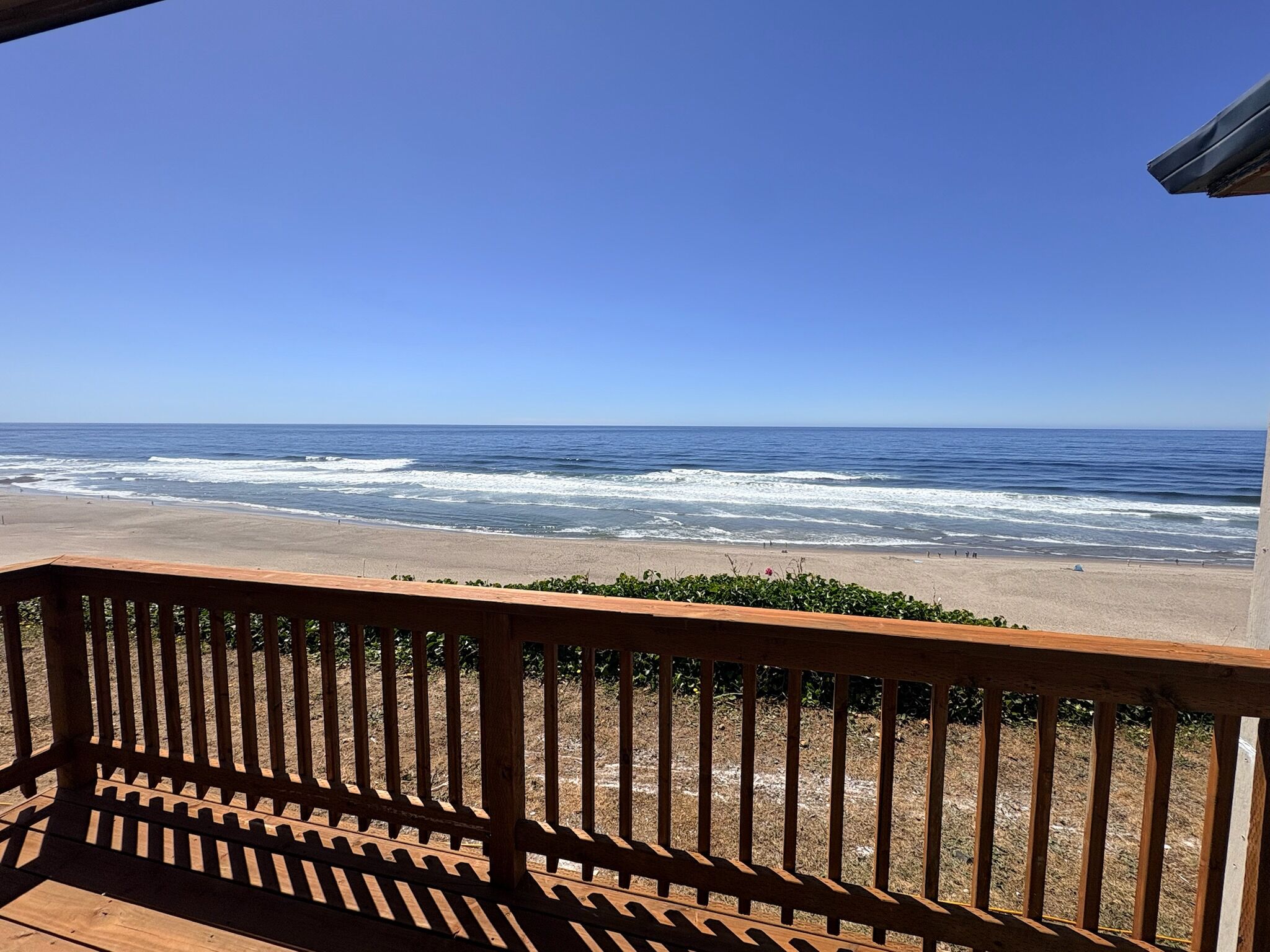 A wooden deck with a view of the ocean and beach.