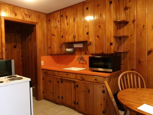 A kitchen with wooden cabinets, a microwave, a stove, and a dining table.