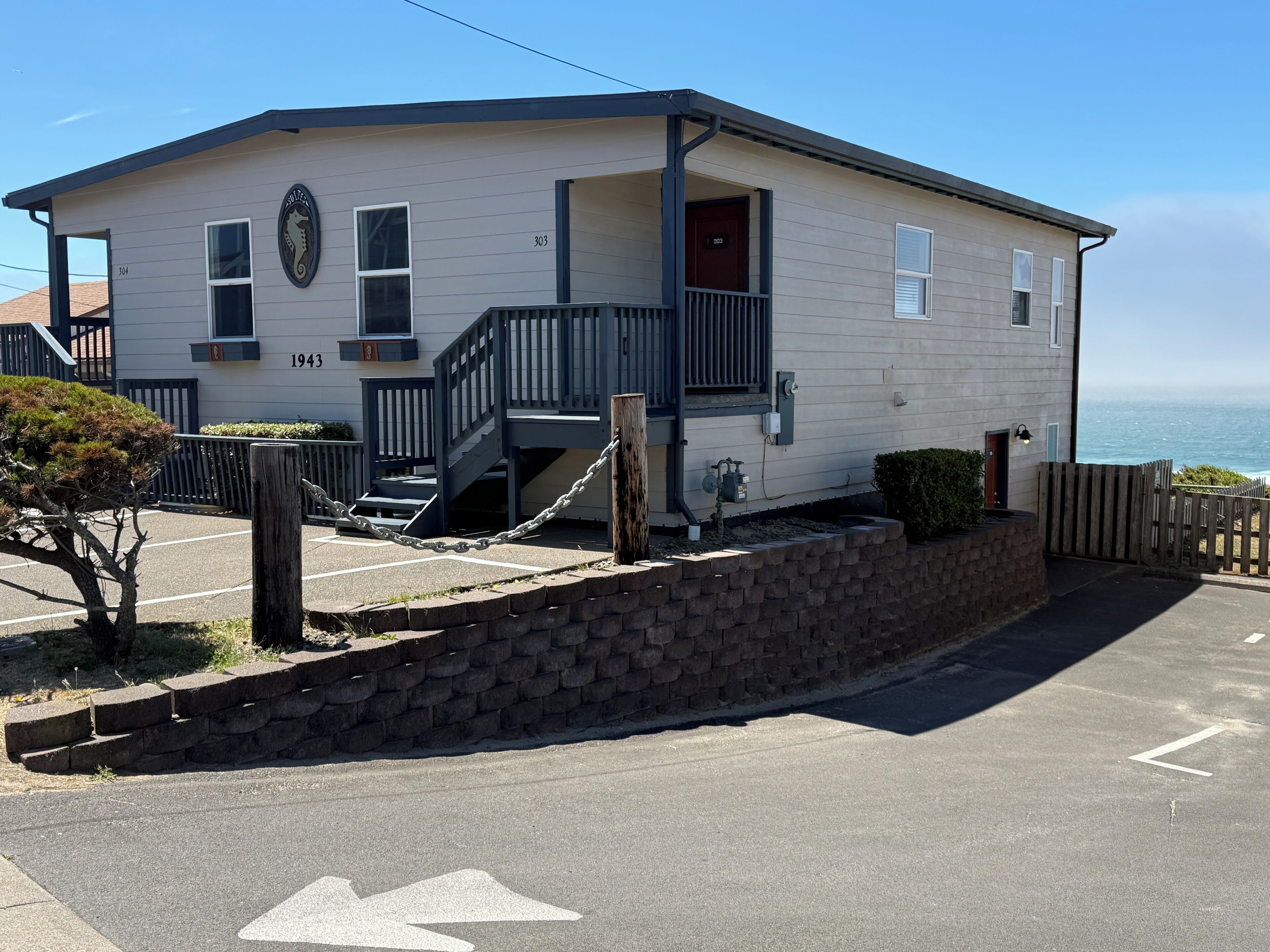 A two-story building with a staircase, a small porch, and a view of the ocean.