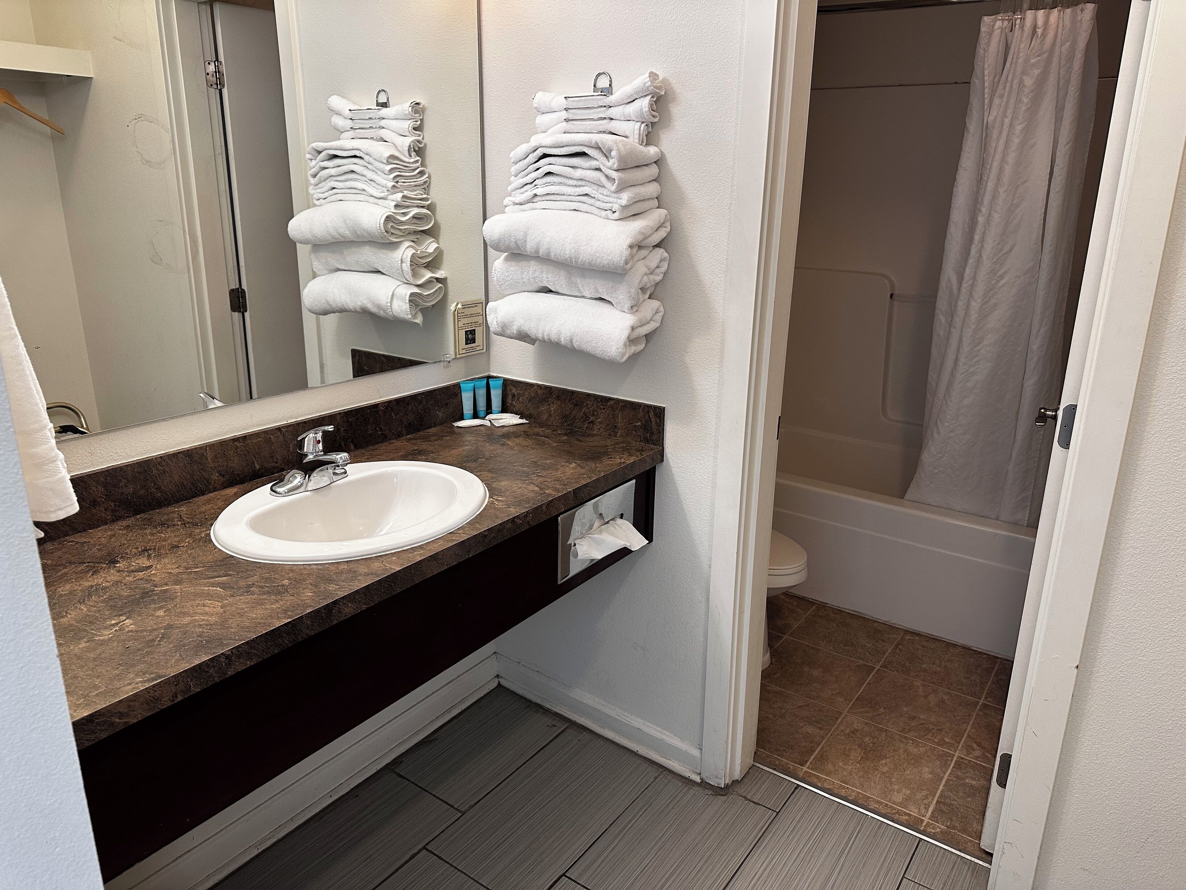 A bathroom with a sink, mirror, towel rack, and shower.
