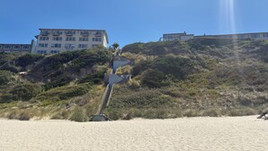 A coastal building with multiple floors, a staircase leading up to it, and a sandy beach in the foreground. - Seahorse Oceanfront Lodge (Lincoln City)