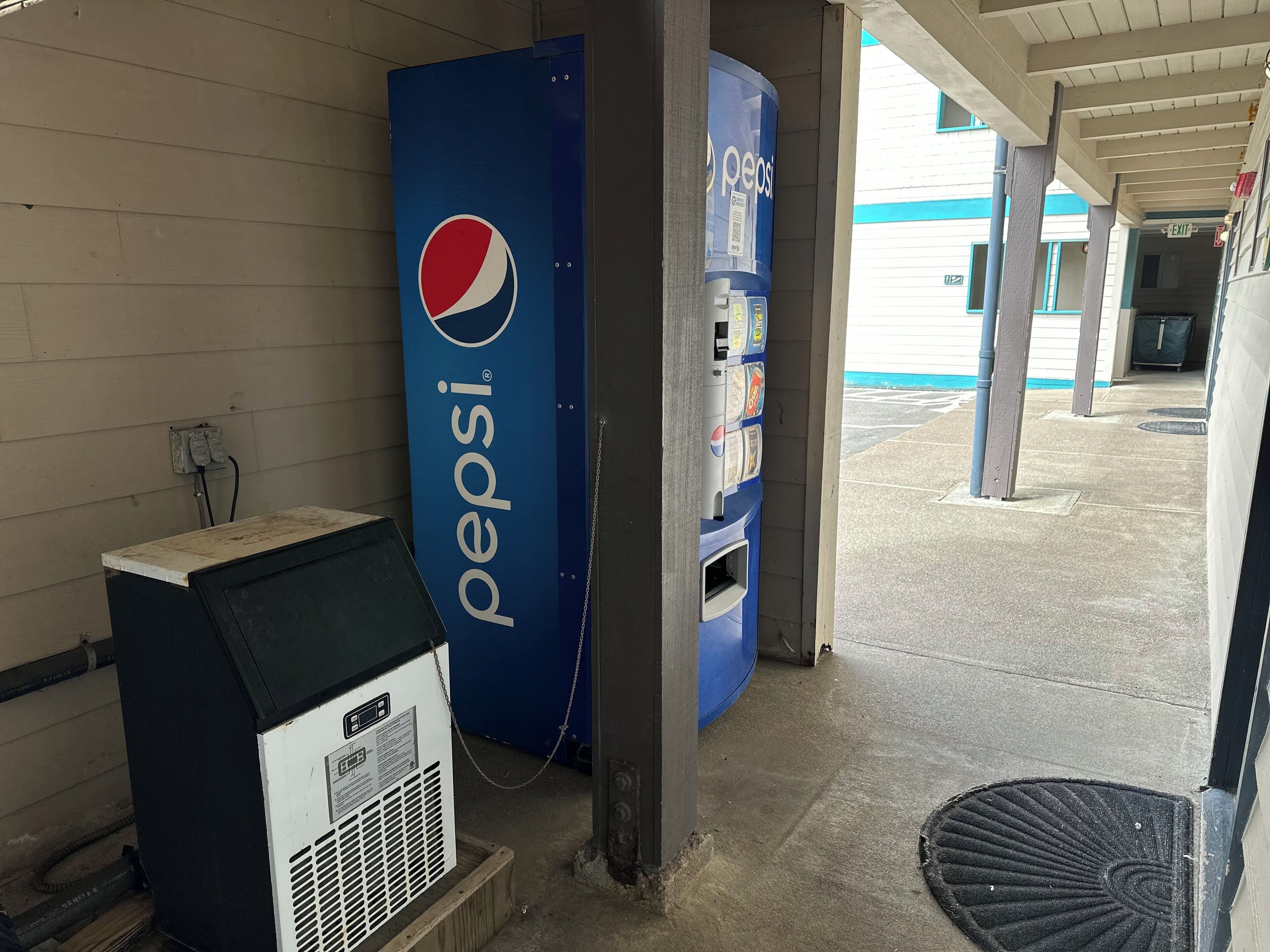 A Pepsi vending machine and an air conditioning unit at a gas station.