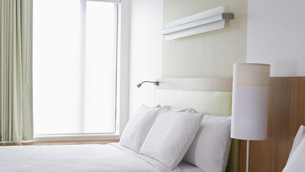 A hotel room with a bed, a bedside table, a lamp, and a window with curtains. - SpringHill Suites by Marriott Philadelphia Langhorne (Langhorne)