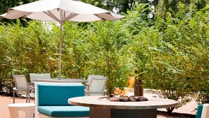 An outdoor seating area with a round table, chairs, and a fire pit. - SpringHill Suites by Marriott Philadelphia Langhorne (Langhorne)