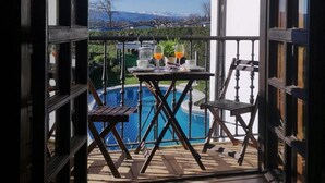 Un balcón con piscina, dos sillas y una mesa con bebidas.