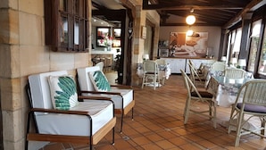 Un restaurante acogedor con mobiliario de mimbre, suelo de baldosas y una decoración rústica.