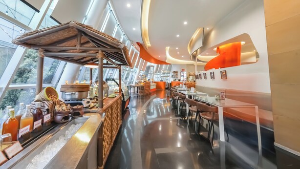 Un restaurant moderne doté d’un comptoir central, d’un espace salon et de grandes fenêtres.