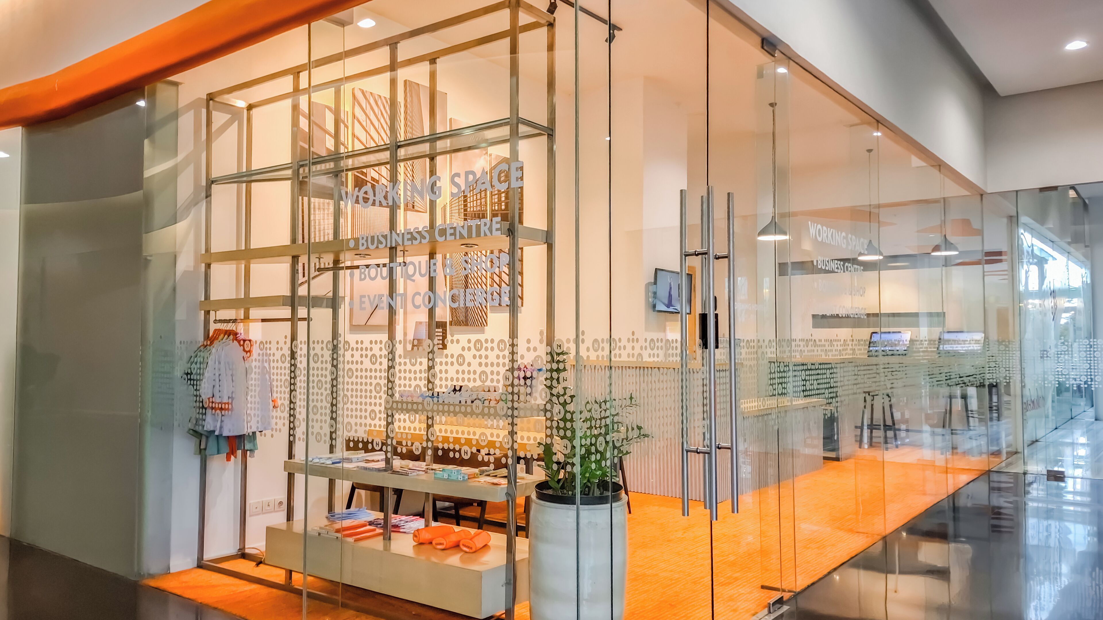 Ein modernes, mit Glasfronten versehenes Boutique-Hotel mit Kleiderständer und einer kleinen Sitzecke.
