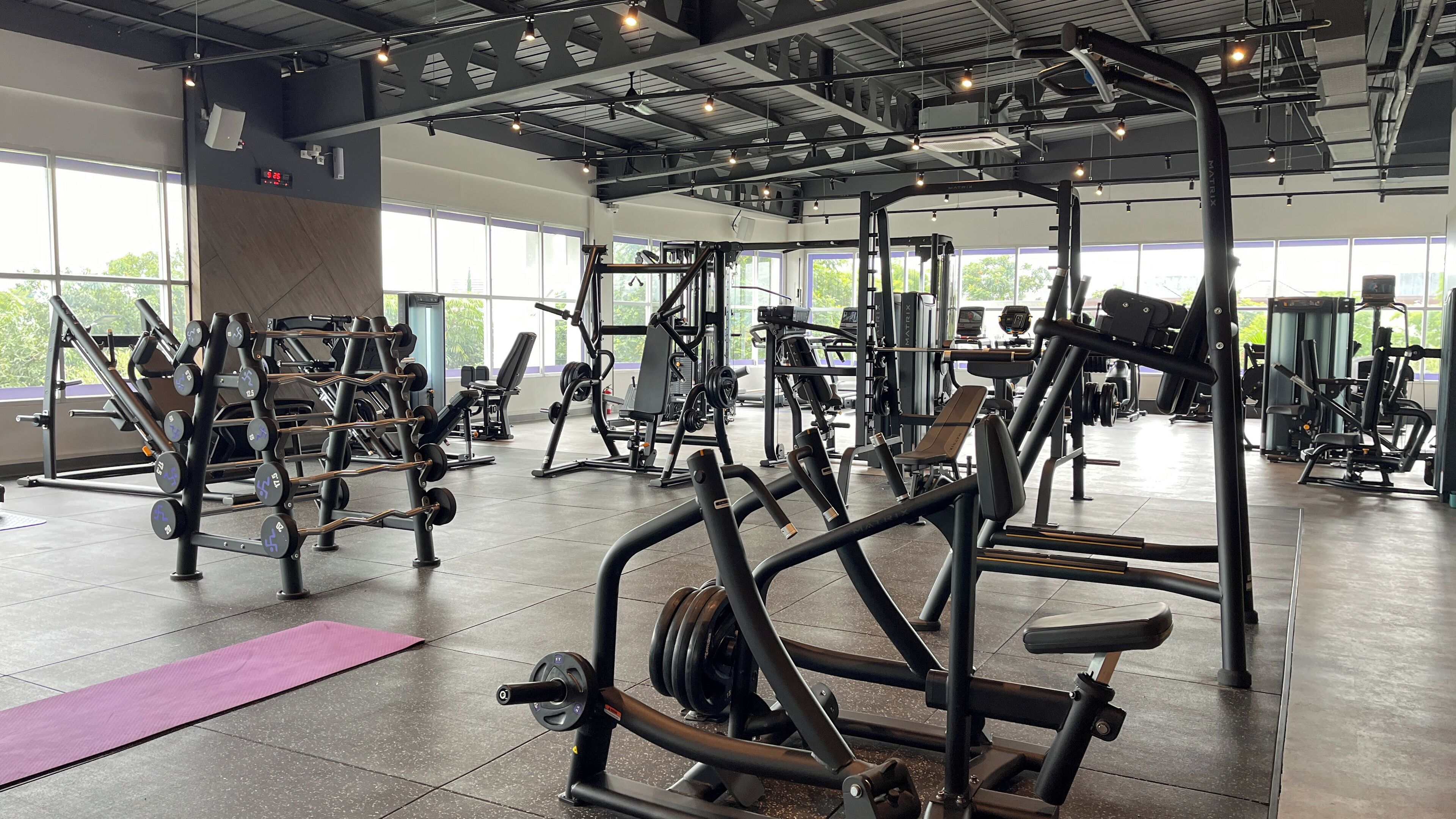 A gym with various exercise equipment, large windows, and a tiled floor.