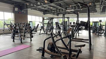 A gym with various exercise equipment, large windows, and a tiled floor.