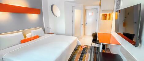 A hotel room with a large bed, a desk, and a mirror.