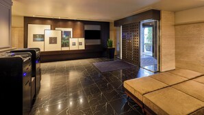 A modern lobby with a marble floor, a seating area, and a wall with framed pictures.