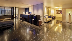 A modern lobby with a reception desk, seating area, and a large artwork on the wall.