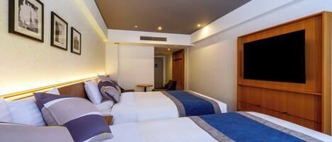 A hotel room with two beds, a TV, and framed pictures on the wall.