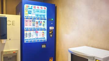Un distributeur automatique proposant une variété de boissons et un four à micro-ondes posé sur un comptoir.