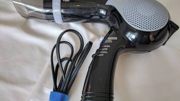 A hair dryer with a clear nozzle, a black handle, and a cord with a blue tie.