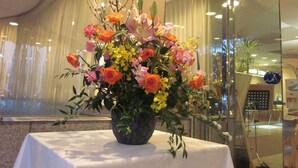 A table with a floral arrangement in a vase. - Hotel Harbour Yokosuka (Yokosuka)