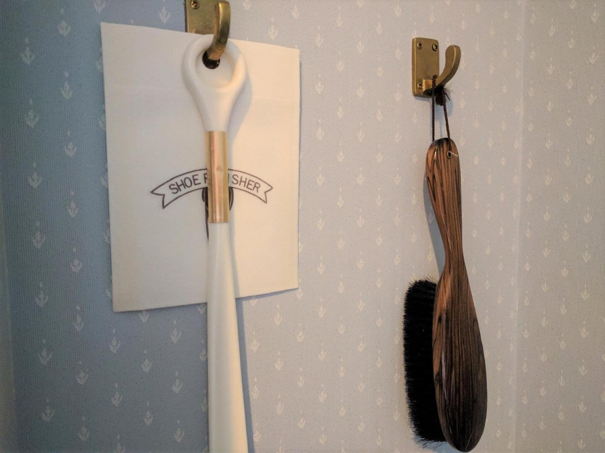 Un modelador de zapatos con un mango blanco y un zapato de madera sobre una pared con un papel tapiz estampado.
