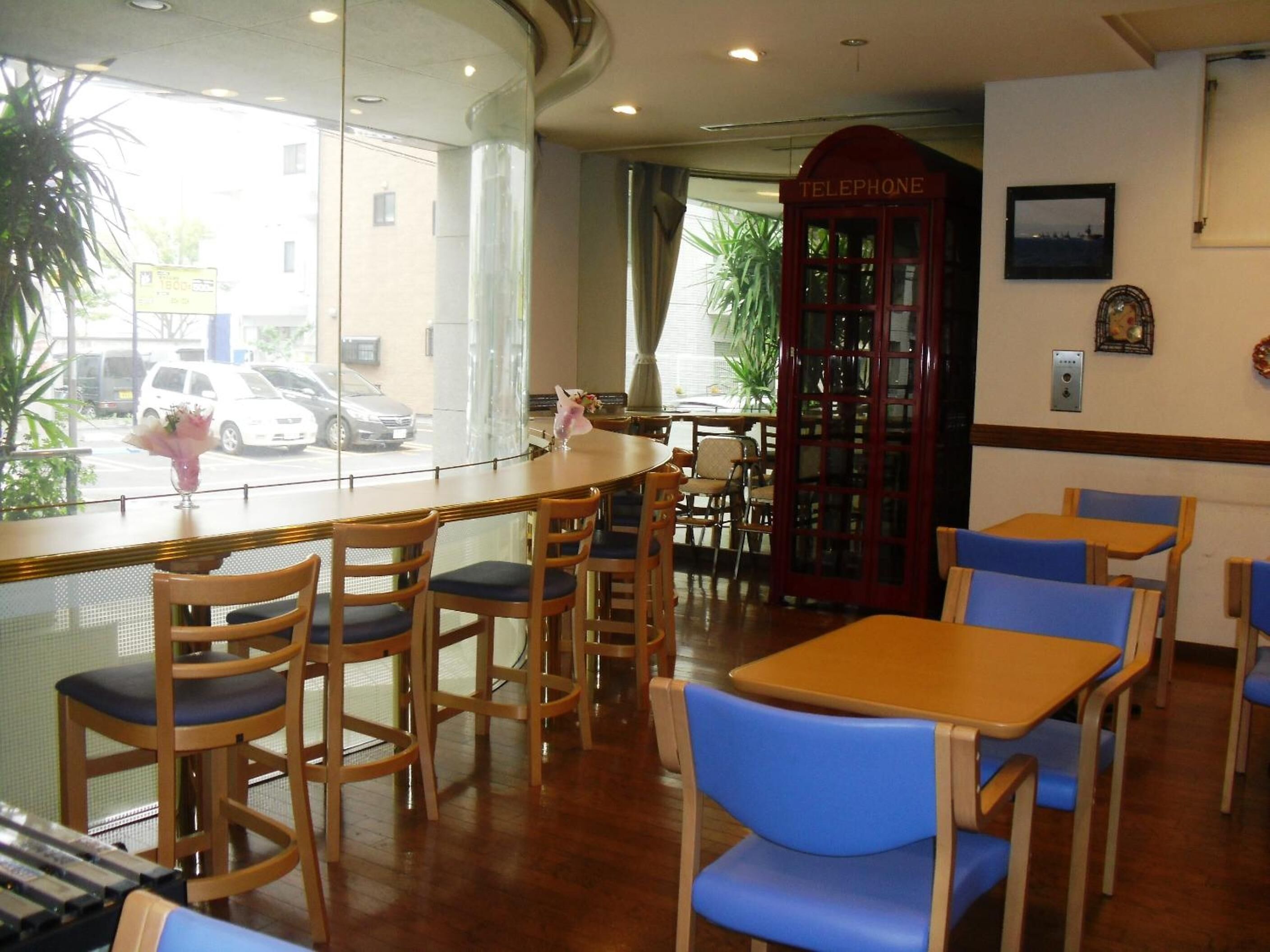 Un restaurant avec des chaises et des tables en bois, un téléphone public et une vue sur la rue.