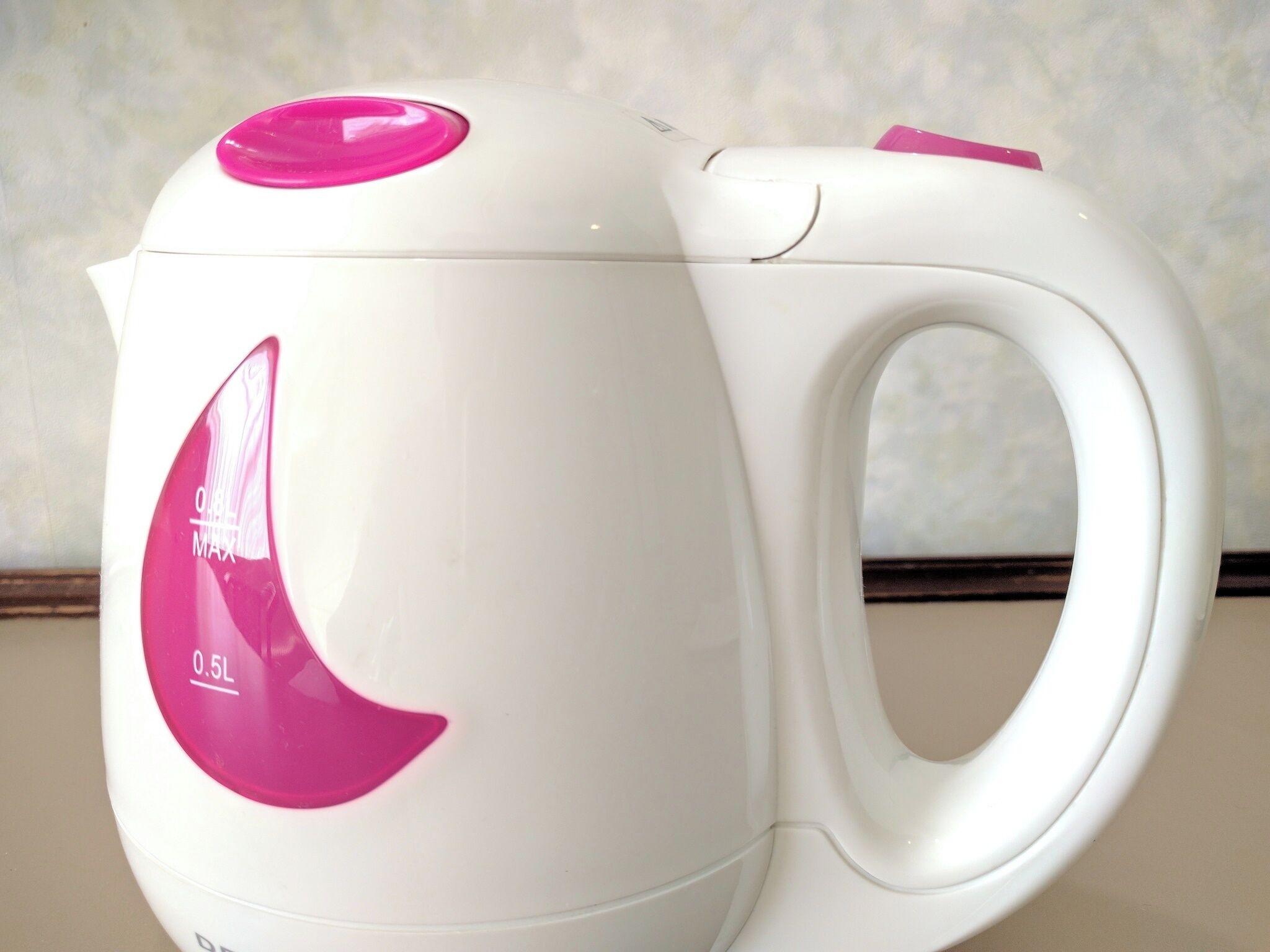 Une bouilloire électrique blanche avec un bouton rose et un indicateur de niveau.