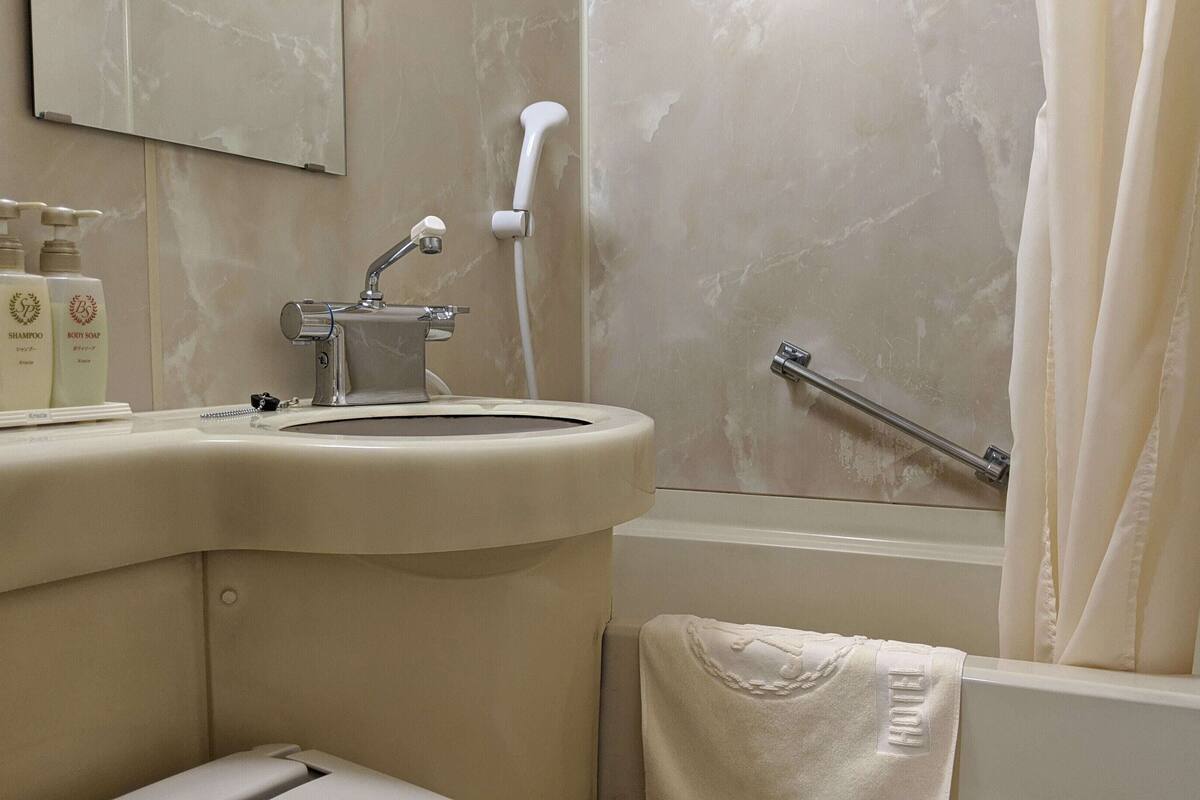 Une salle de bain équipée d’un lavabo, d’un miroir, d’une douche et d’un porte-serviettes.