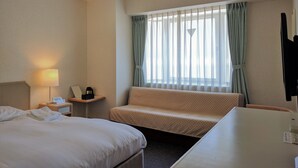 A hotel room with two beds, a desk, a lamp, a chair, and a window with curtains. - Hotel Harbour Yokosuka (Yokosuka)