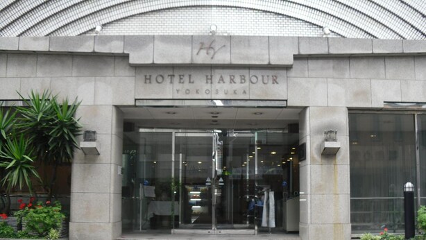 The entrance to Hotel Harbour in Yokosuka, featuring a modern glass facade and a stone base. - Hotel Harbour Yokosuka (Yokosuka)