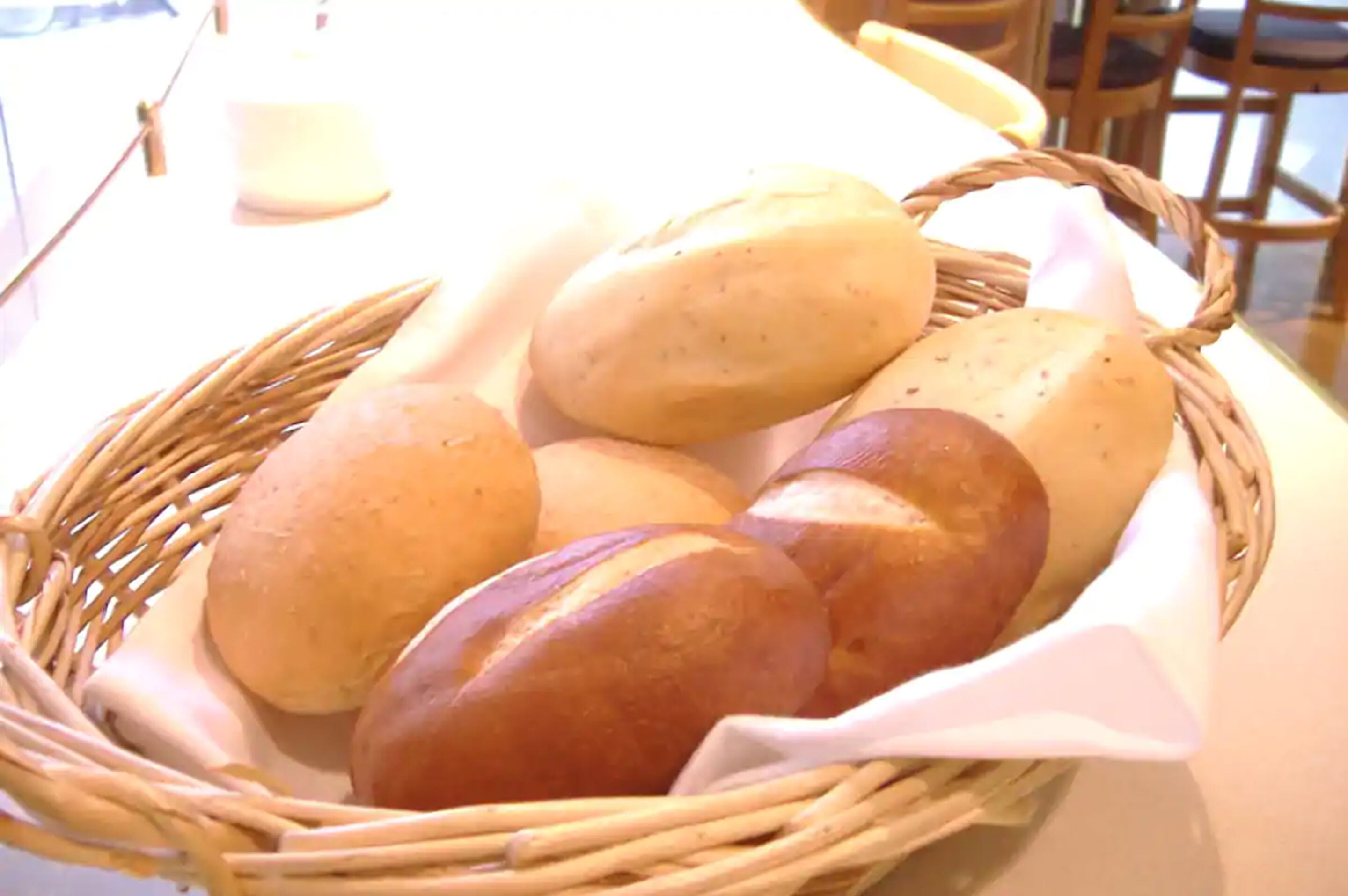A basket of bread rolls on a table.