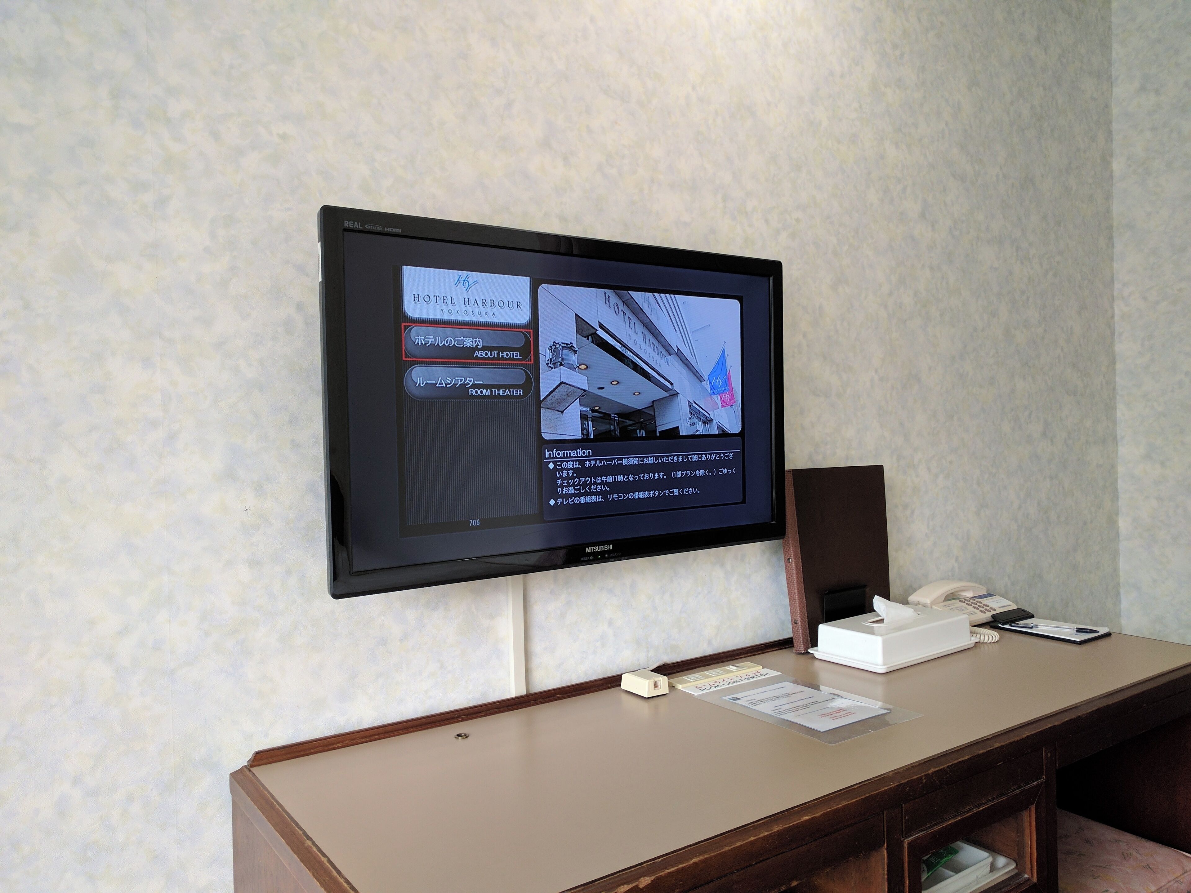 A hotel reception desk with a mounted television displaying hotel information.