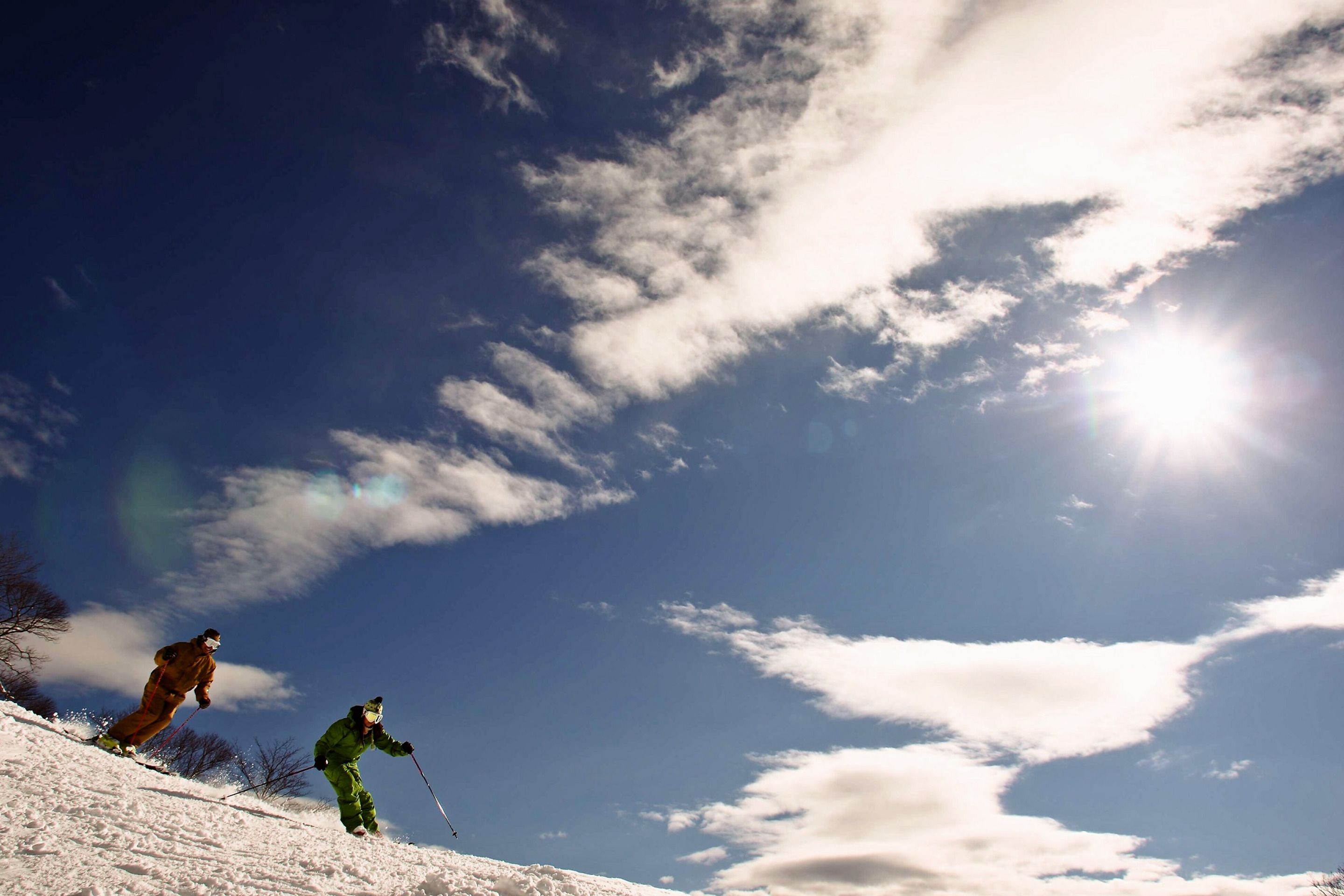 Two skiers on a snowy slope under a clear sky.