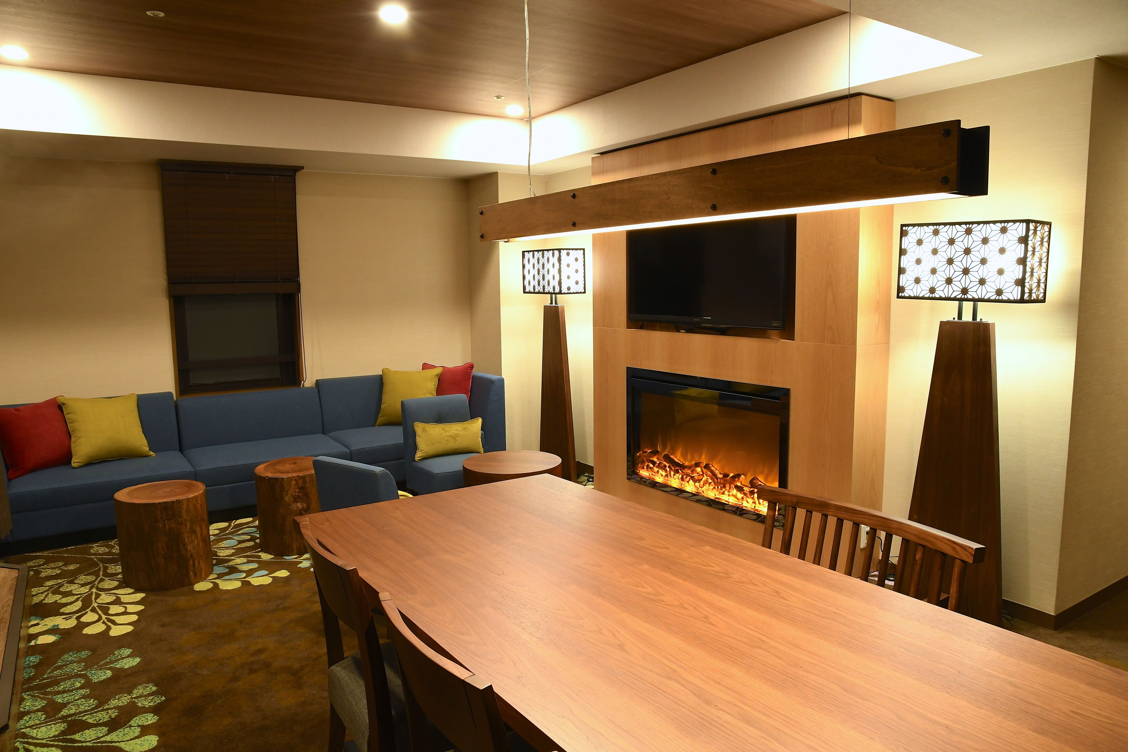 Una sala de estar moderna con una mesa de comedor de madera, un sofá azul y una chimenea.