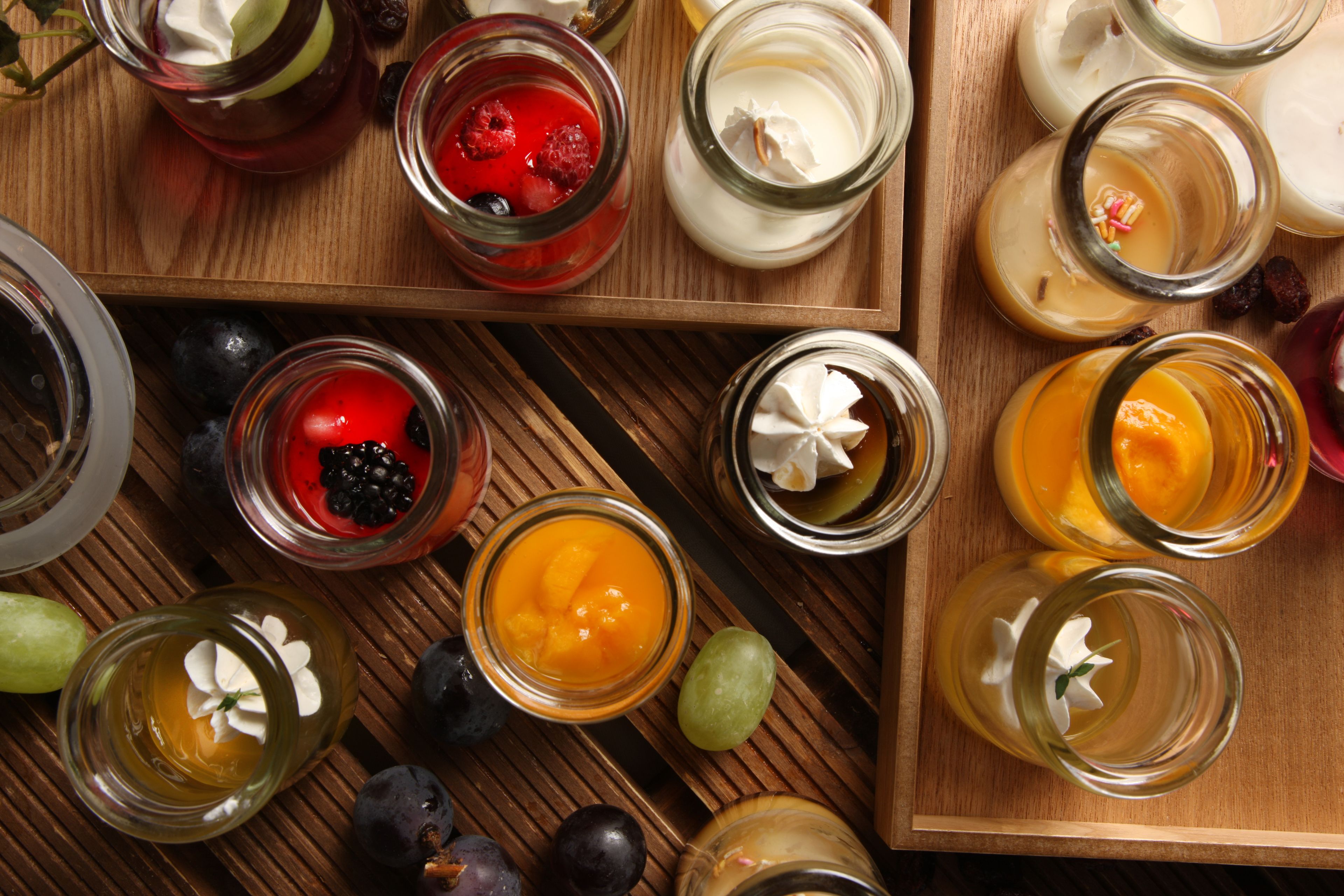 A wooden tray with various glass jars containing different types of food and garnishes.