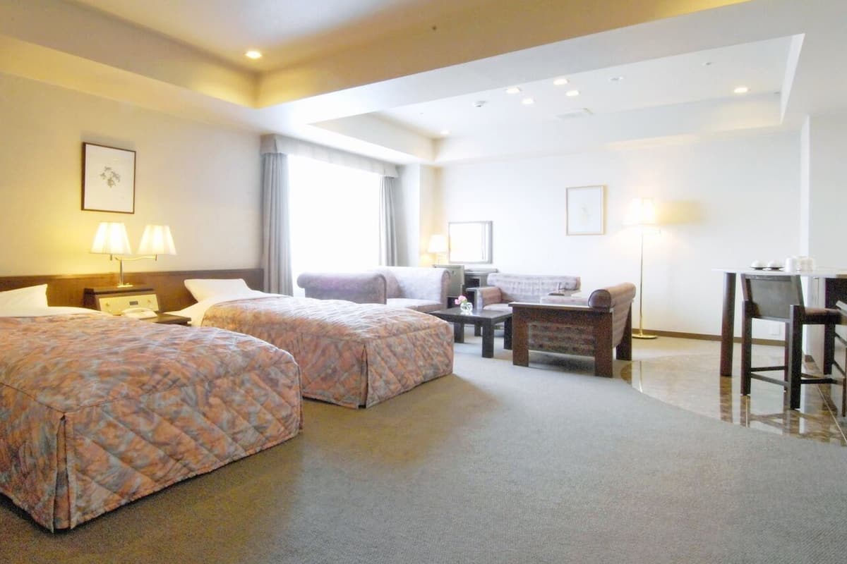 Een hotelkamer met twee bedden, een bureau, een stoel en een bank.