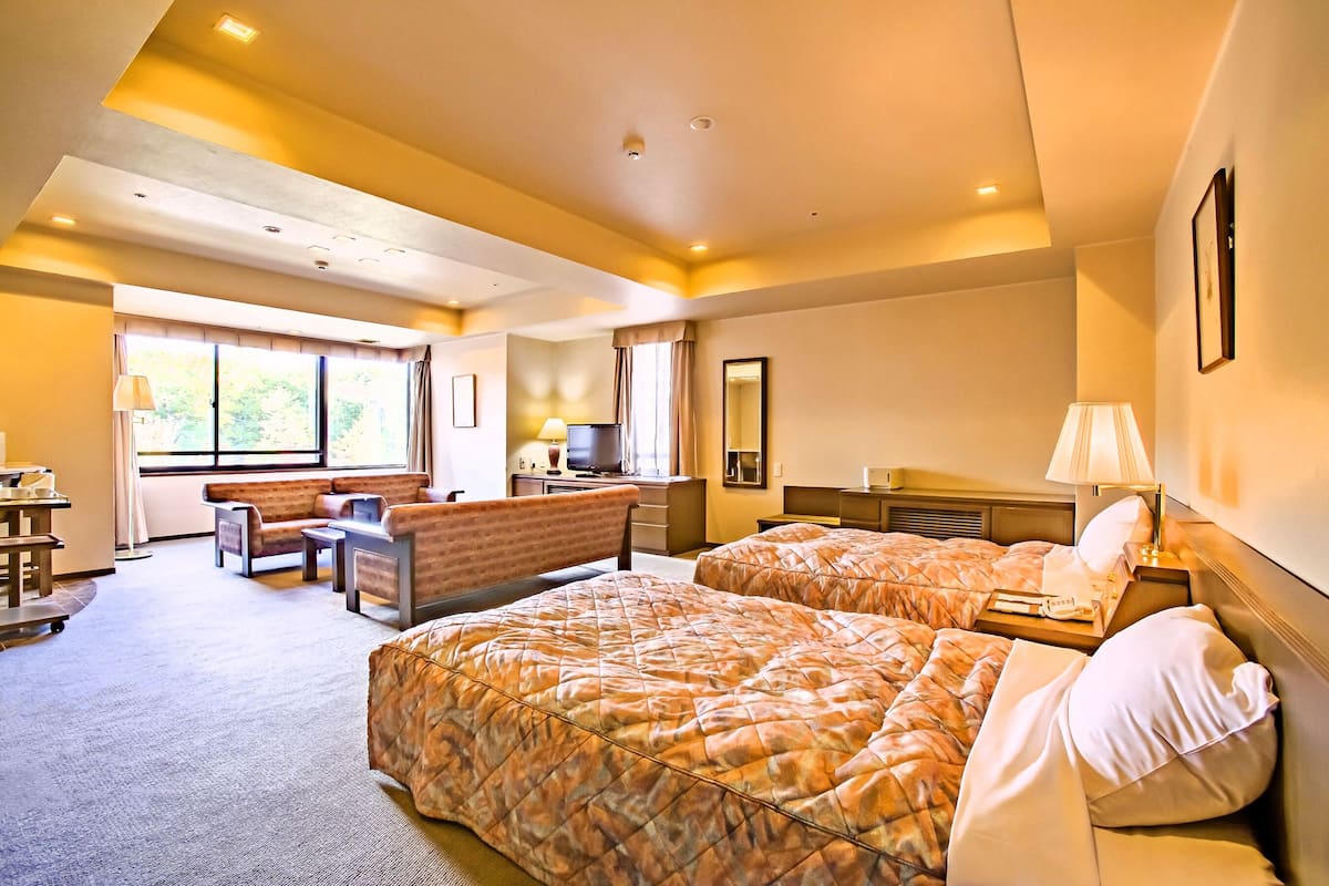 Een hotelkamer met twee bedden, een bank, een bureau en een televisie.
